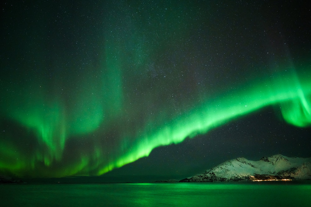 The water lit up to a bold green color on a relatively clear night near Rekvik, Norway.