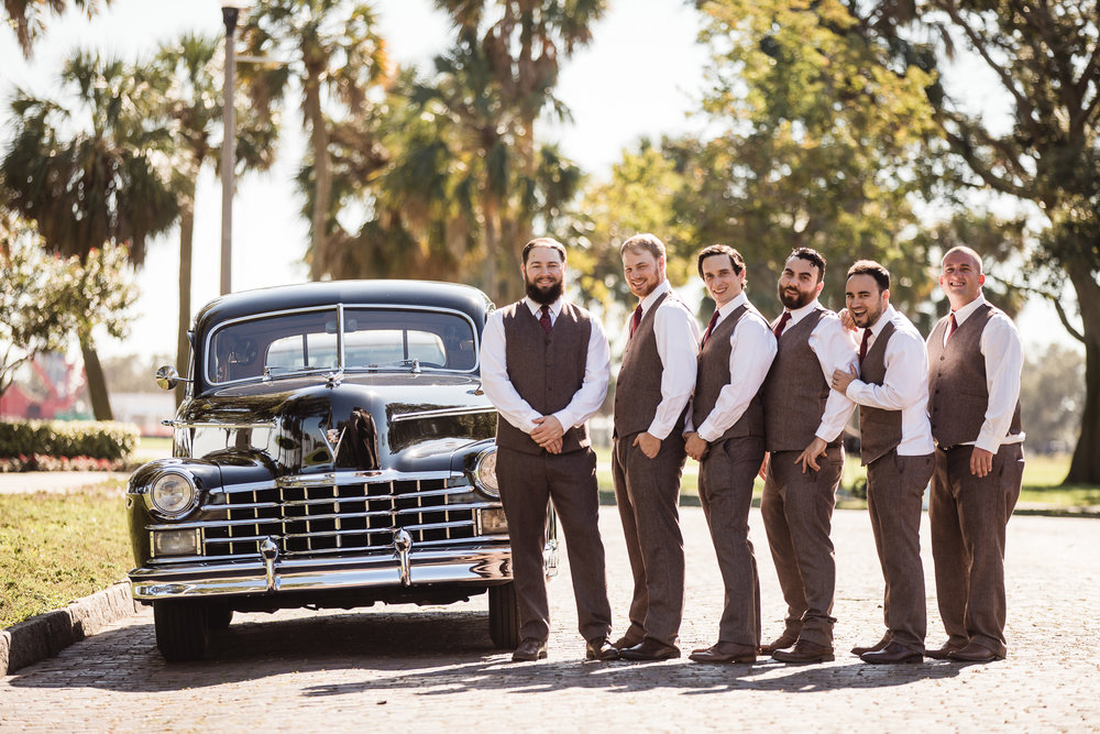 Grooms standing with groomsmen and a classic car before a wedding at Vinoy Park in St. Petersburg, Florida