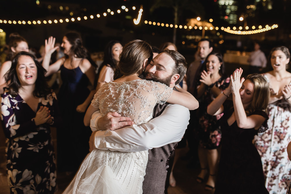 Fun nighttime wedding reception photograph of bride and groom hugging while dancing at The St. Petersburg Shuffleboard Club