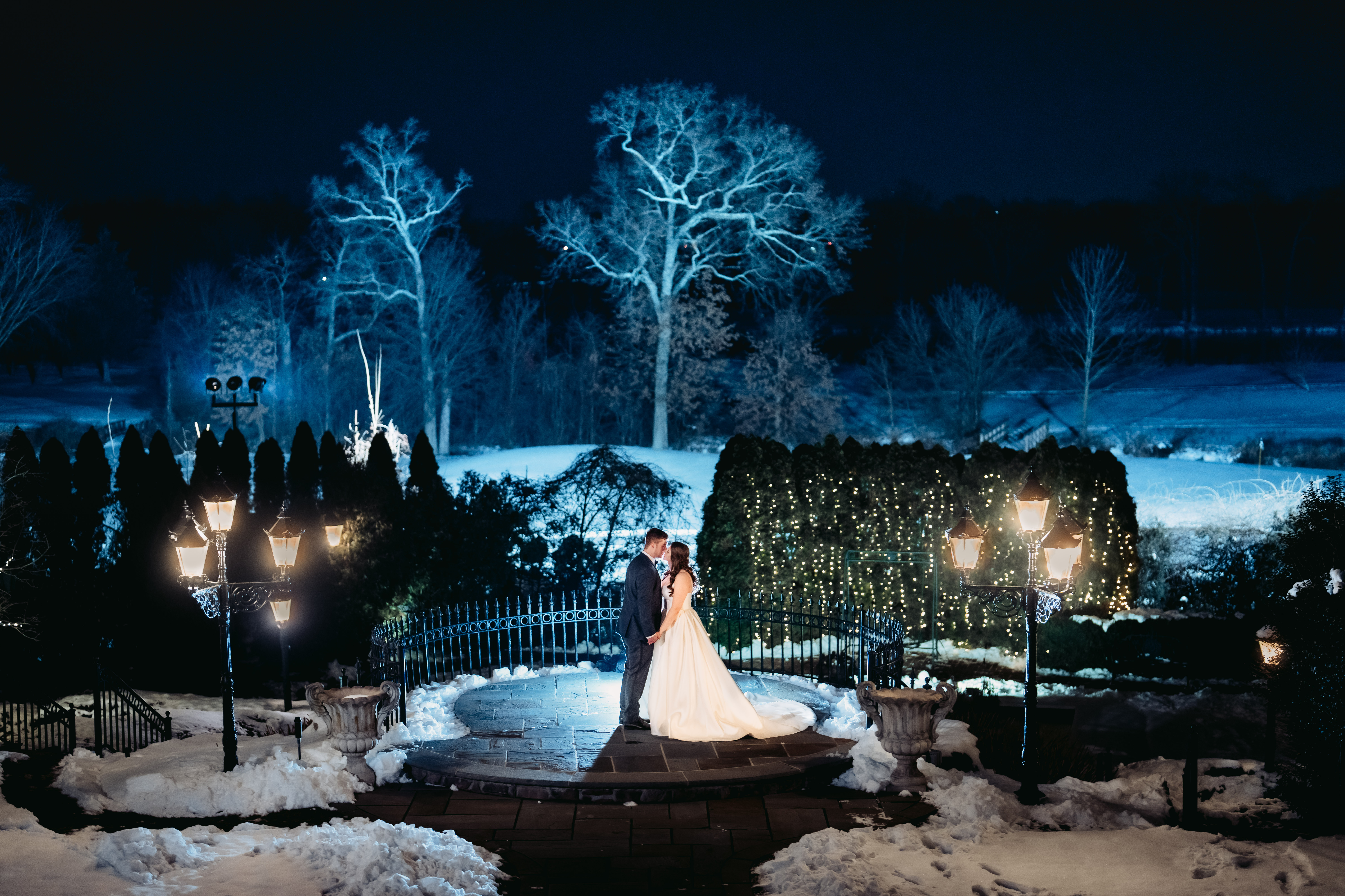Park Savoy Wedding, Park Savoy Wedding Photographer, Florham Park Wedding Photographer, Morris County Wedding Photographer, Winter Wedding, NJ Winter Wedding, NJ Photographer, NJ Wedding Photographer, bride and groom kissing outside the Park Savoy with the grounds covered in snow and they are being back lit by a blue light 