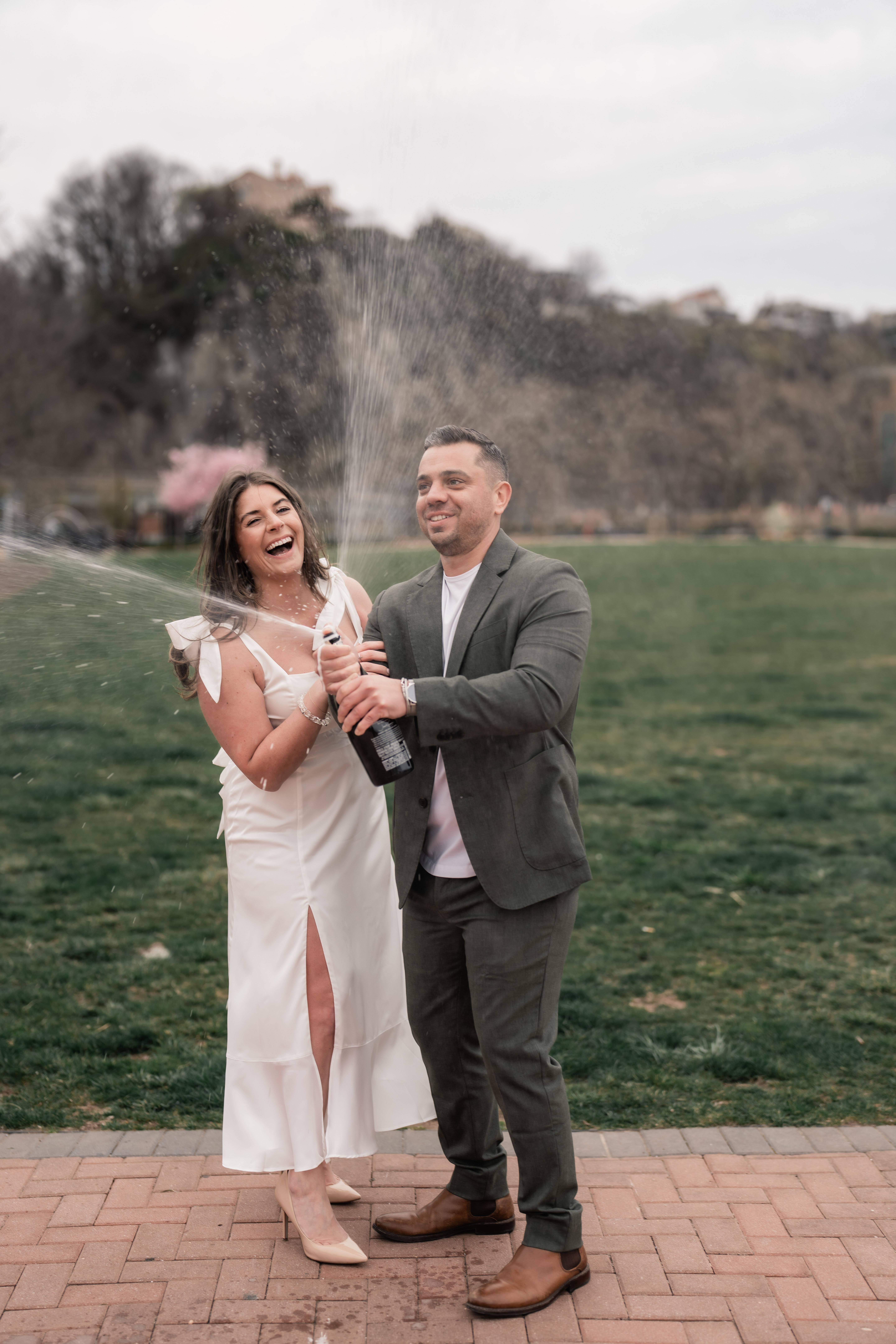 Hoboken Engagement, Hoboken NJ Engagement, Hoboken Engagement Session, Hoboken NJ Engagement Photographer, NJ Engagement Photographer, couple smiling and laughing while spraying a bottle of champagne 