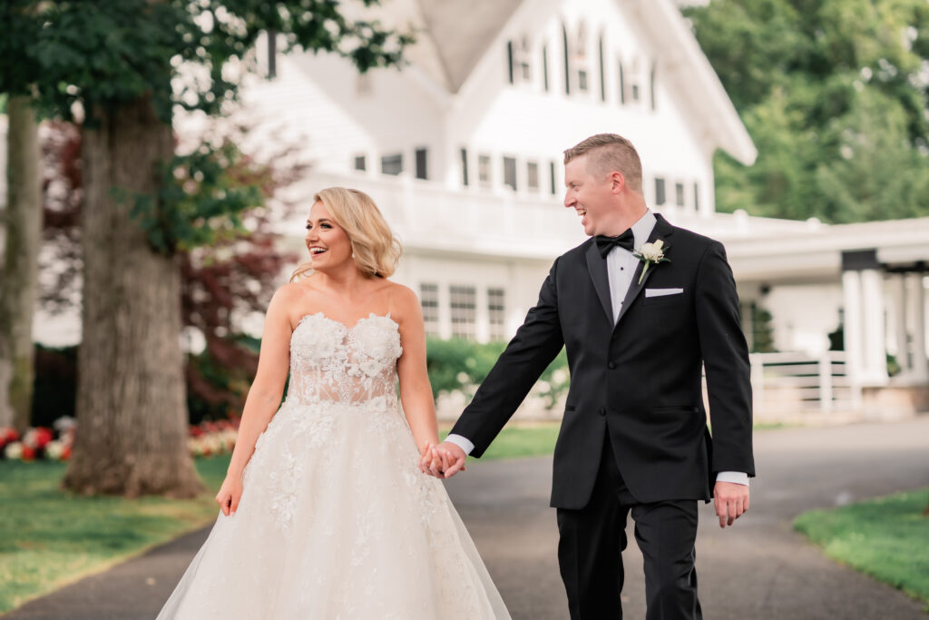 Ryland Inn Wedding Photographer, NJ Weddings, New Jersey Wedding Photographer, NJ Wedding Photographer, New Jersey Wedding Venues, Wedding Photography, Wedding Inspiration, Wedding Planning, Wedding Ideas, Unique Wedding Photos, Wedding Photo Ideas, Bride and Groom smiling and holding hands while walking outside the Ryland Inn on their wedding day