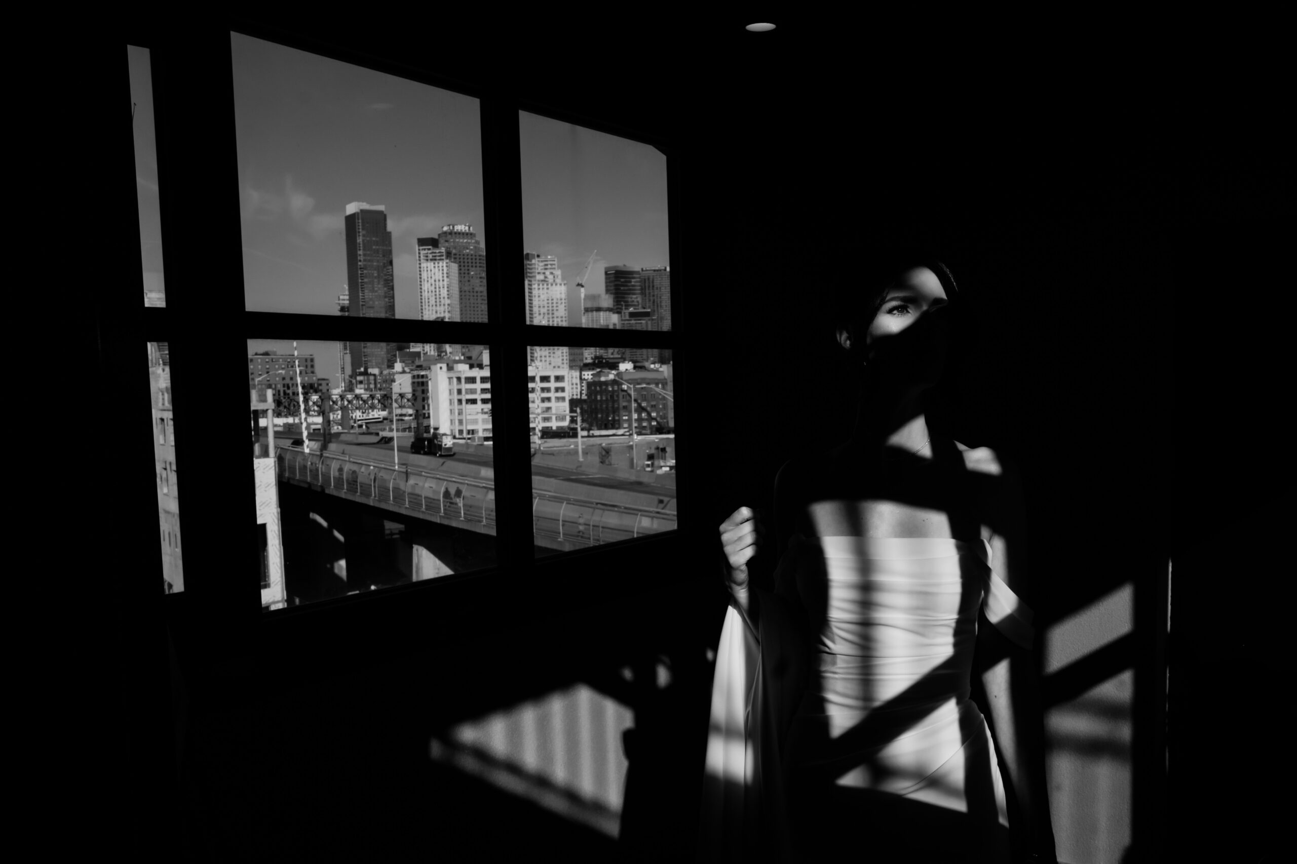 Box House Hotel Wedding, Brooklyn Wedding Photographer, NYC Wedding Photographer, NJ Wedding Photographer, Brooklyn Chic Wedding, Brooklyn Wedding Venue, NYC Wedding Venue, NYC Wedding, Disco Ball Wedding, Wedding Photo Inspiration, Wedding Photo Ideas, Cinematic Wedding Photography, Documentary Wedding Photography, creative black and white portrait of bride standing in direct sunlight darkened by a  grid of shadows from a large window and NYC buildings in the background