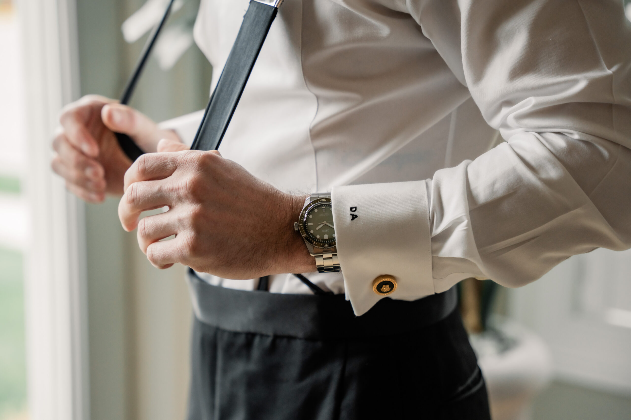 New Jersey wedding detail photography showing the groom fastening his black tie beside a window before the Park Loft wedding ceremony.