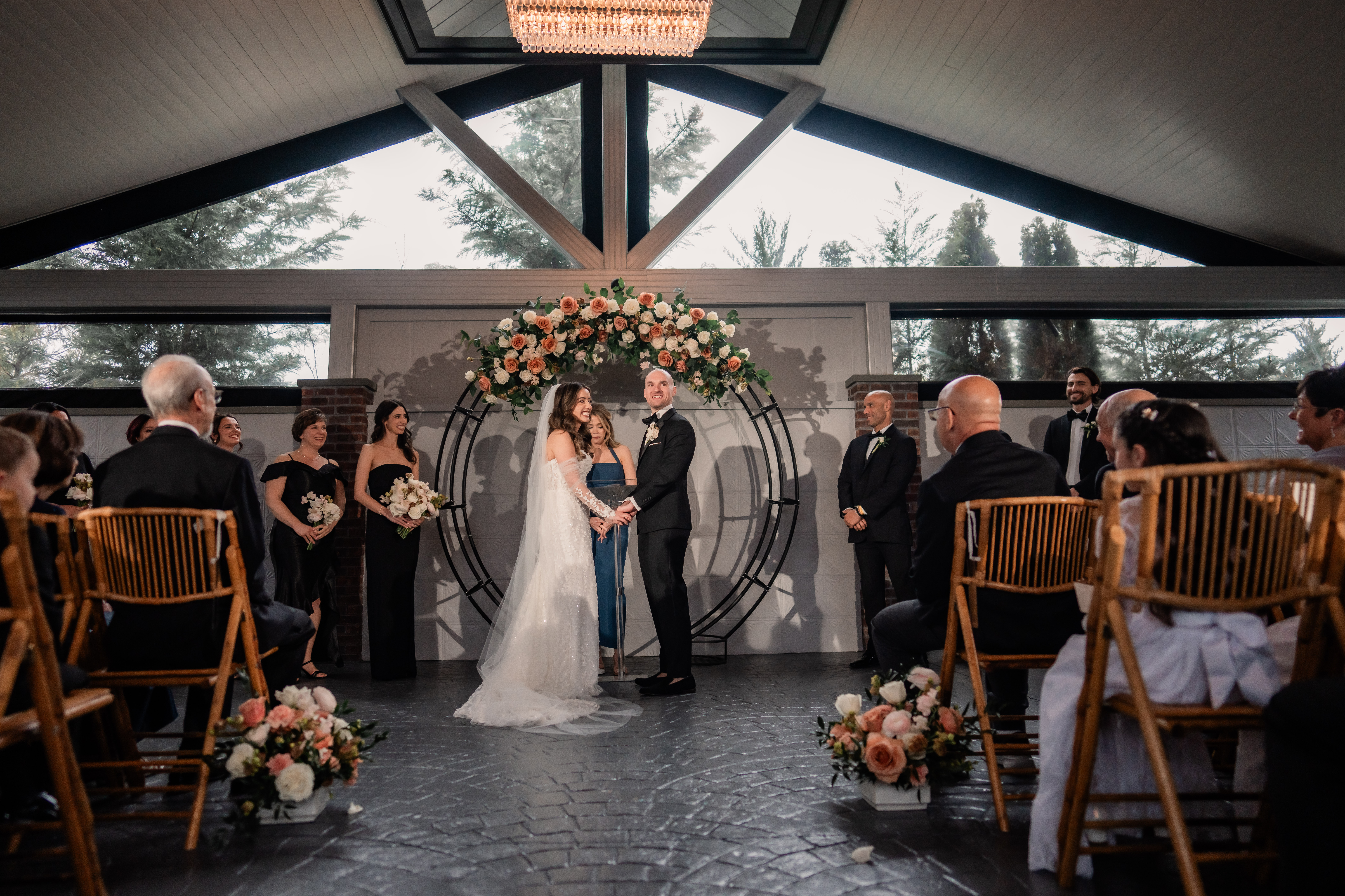 Park Loft wedding ceremony in Oceanport, NJ, with the bride and groom standing beneath a floral arch inside the Belvedere ceremony space.