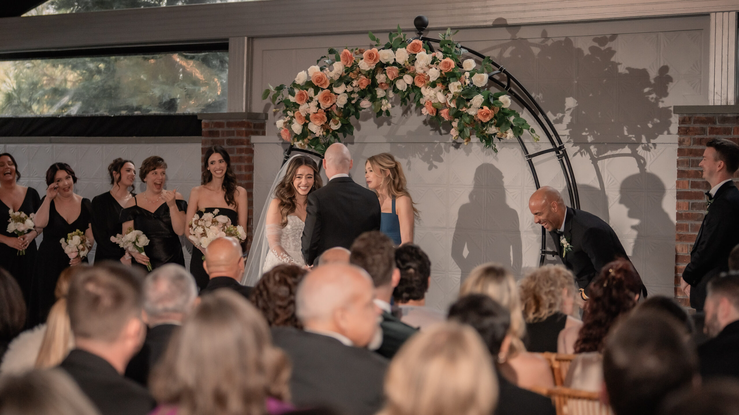 Candid Park Loft wedding photography showing the bride laughing during the ceremony while the wedding party and guests look on.