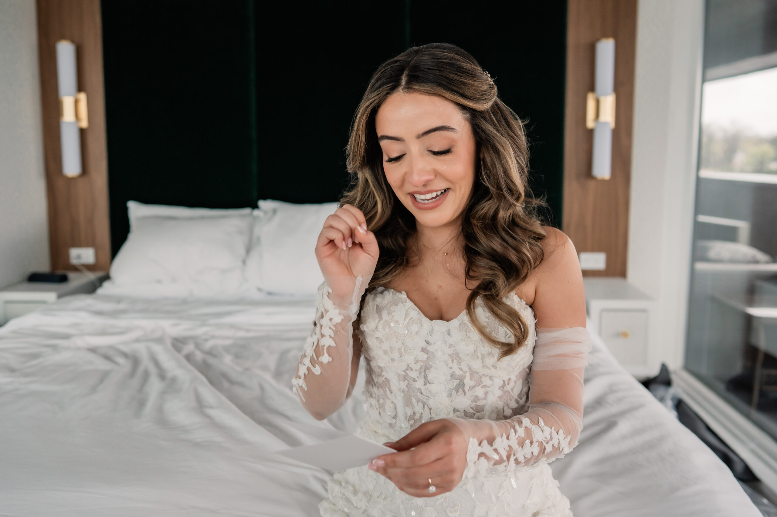 Candid bridal portrait from a Park Loft wedding day, with the bride smiling while reading an emotional letter from the groom.