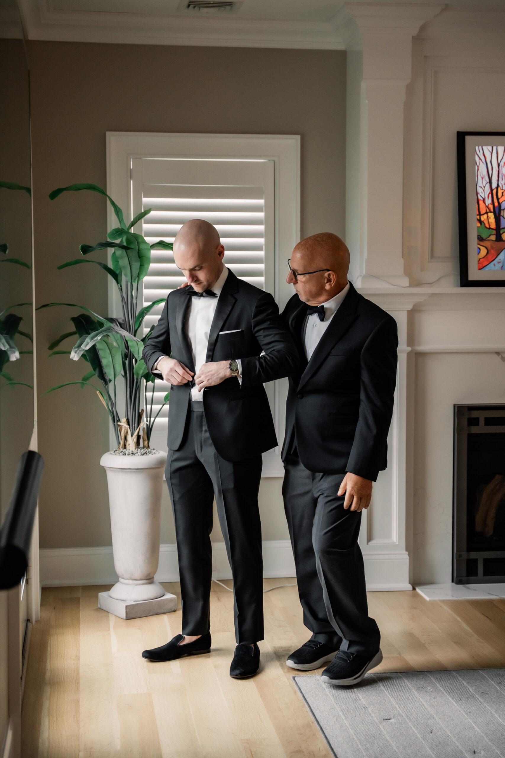 Groom getting ready for his Park Loft wedding in Oceanport, NJ, with a family member helping adjust his tuxedo jacket.