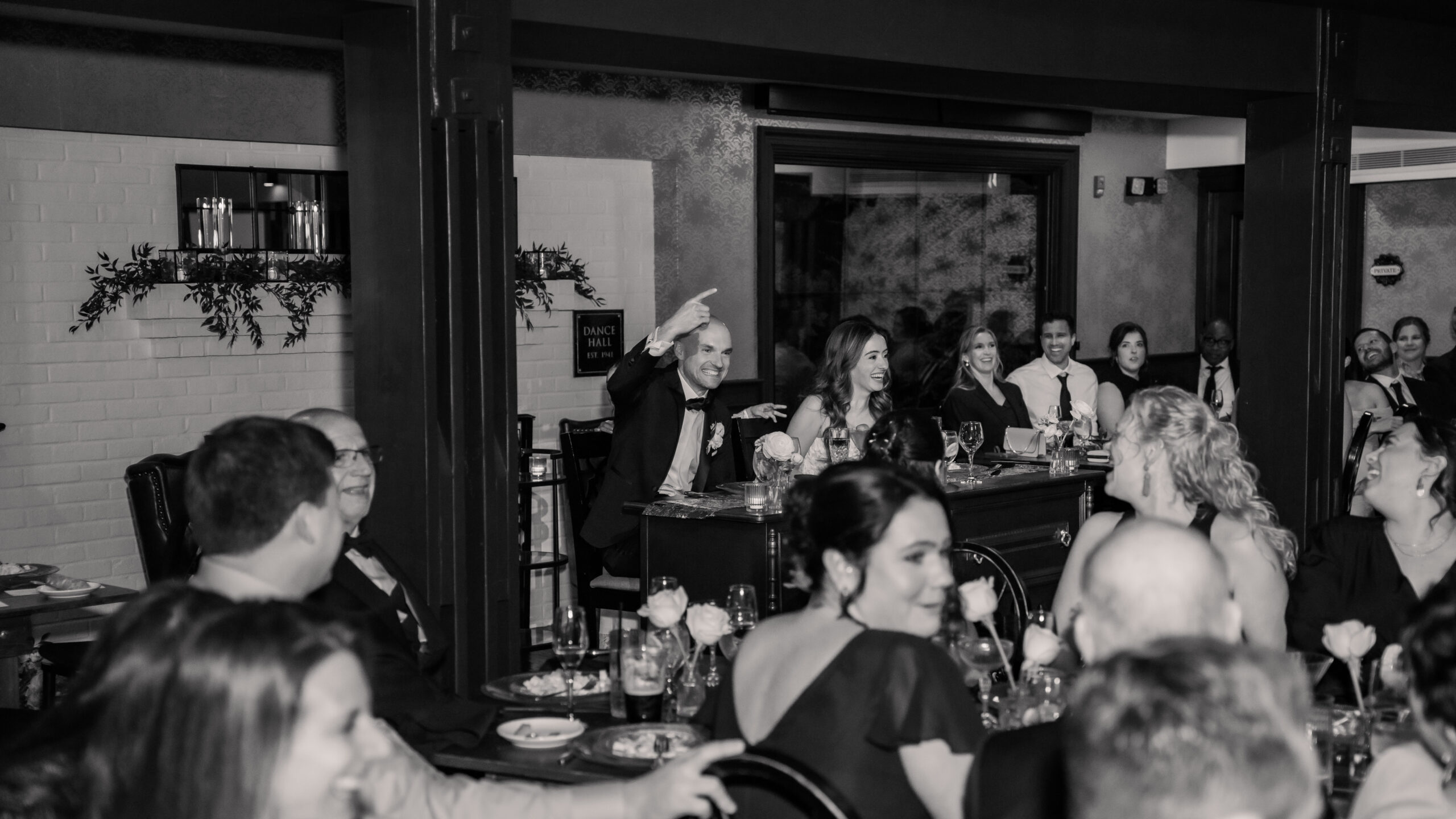 Black-and-white candid Park Loft wedding photography capturing the newlyweds laughing and reacting during reception speeches.