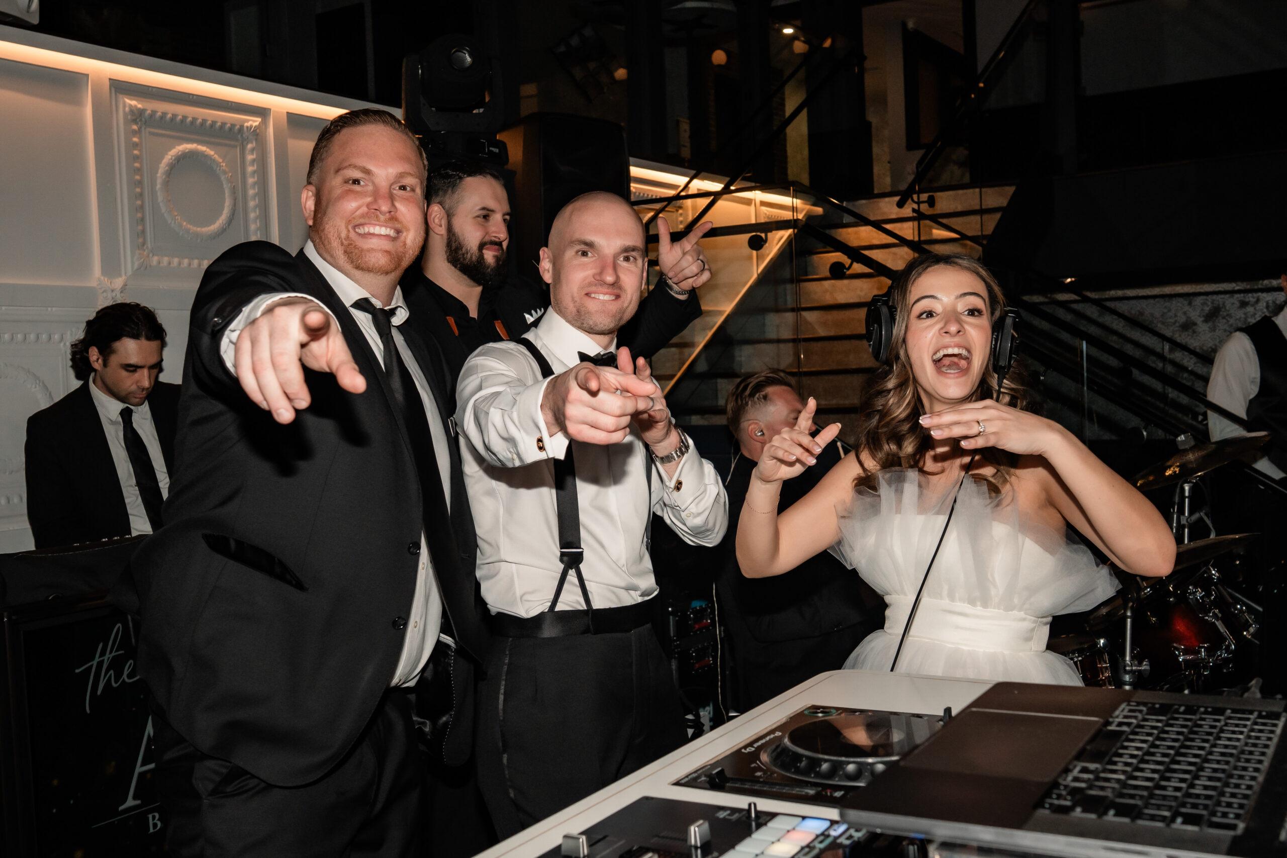 Playful Park Loft wedding reception photography showing the bride and groom partying behind the DJ booth with friends in Oceanport, NJ.
