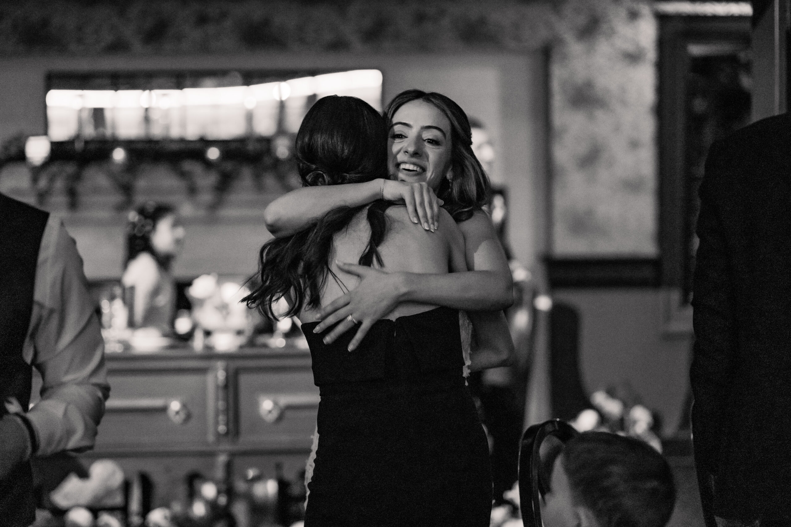 Black-and-white candid Park Loft wedding photography capturing the bride hugging a guest during the reception.