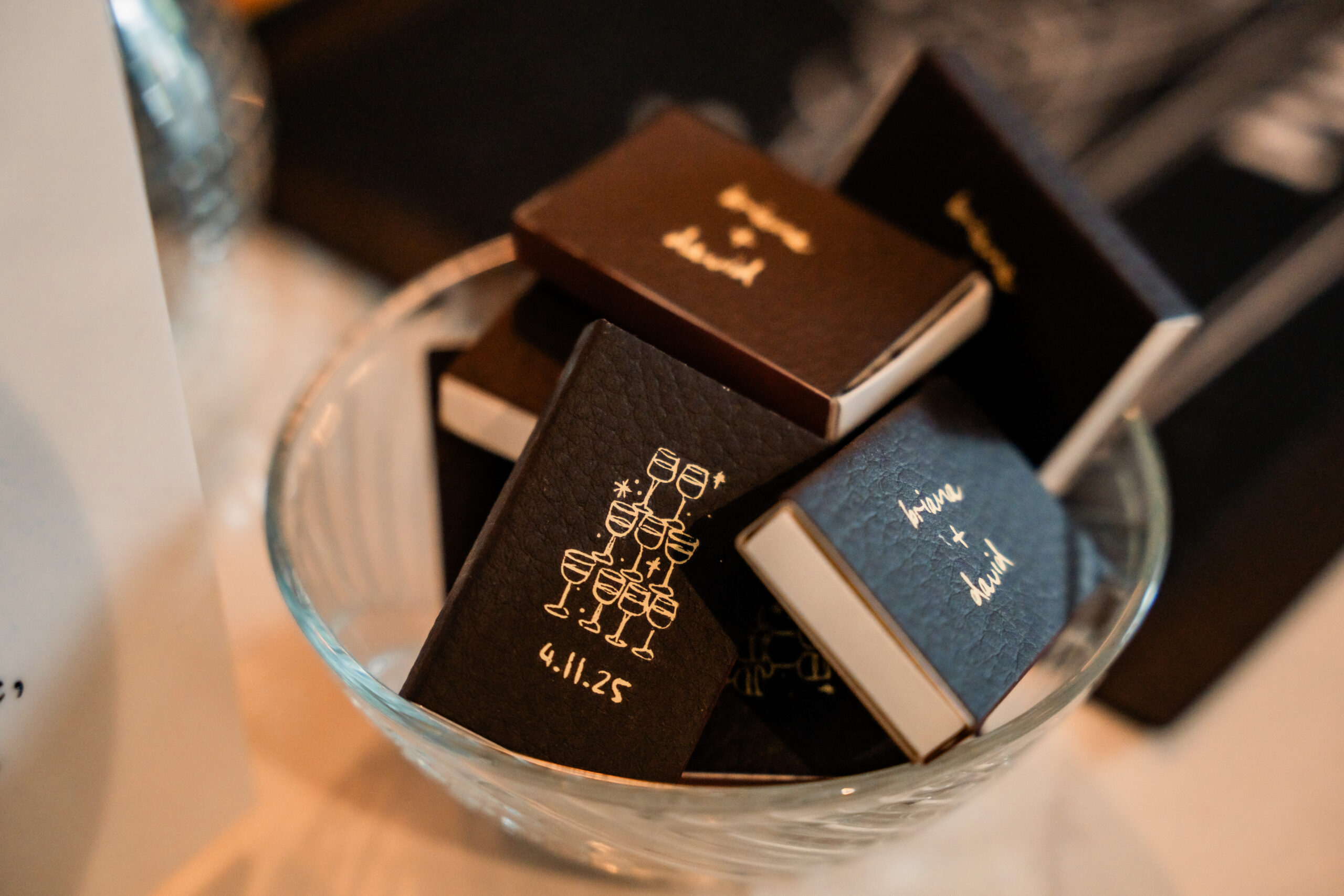 Custom wedding matchbooks displayed as favors during a stylish Park Loft wedding reception in New Jersey.