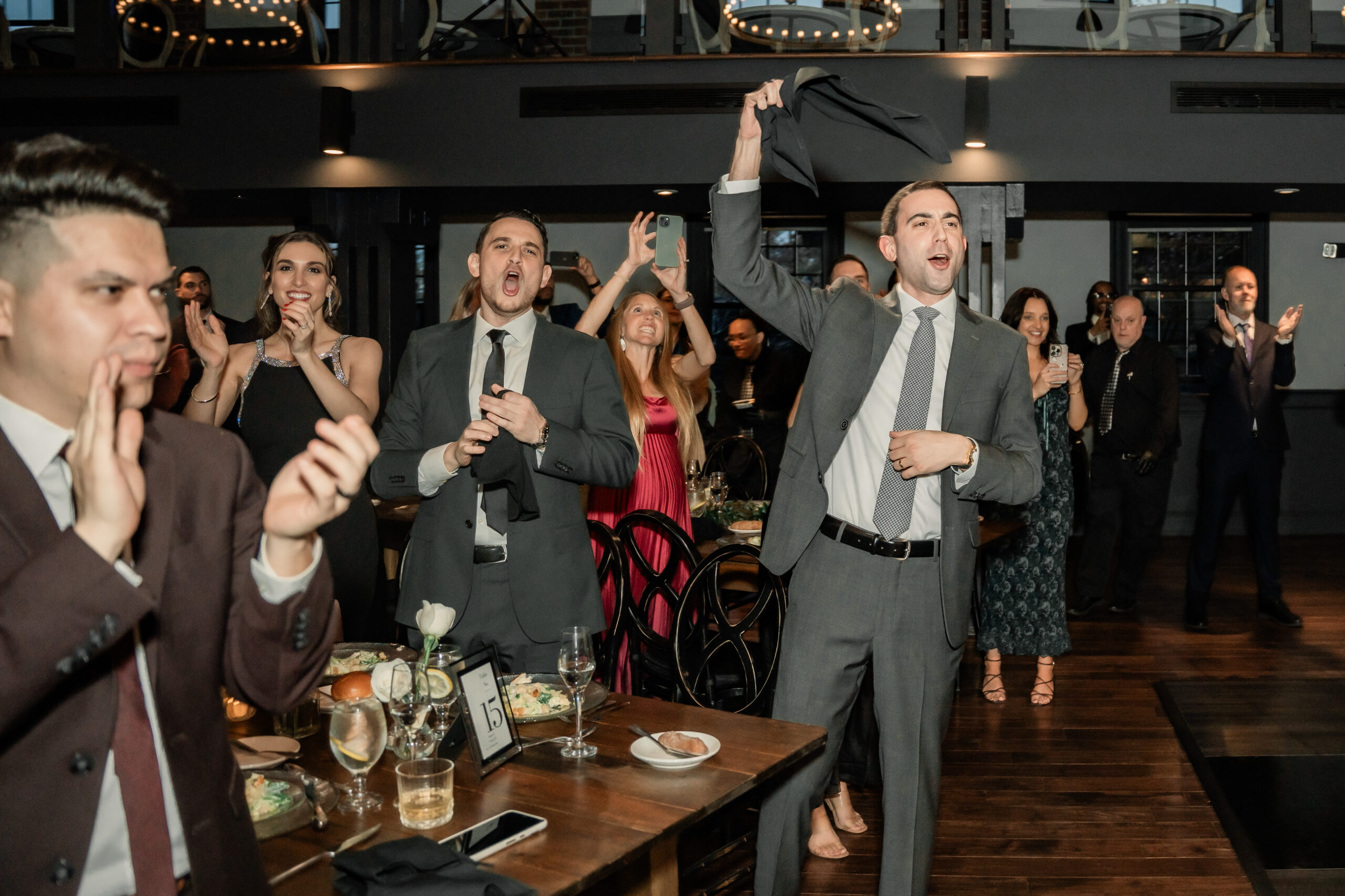 Energetic Park Loft wedding reception in Oceanport, NJ, with guests cheering during the newlyweds’ entrance into the ballroom.