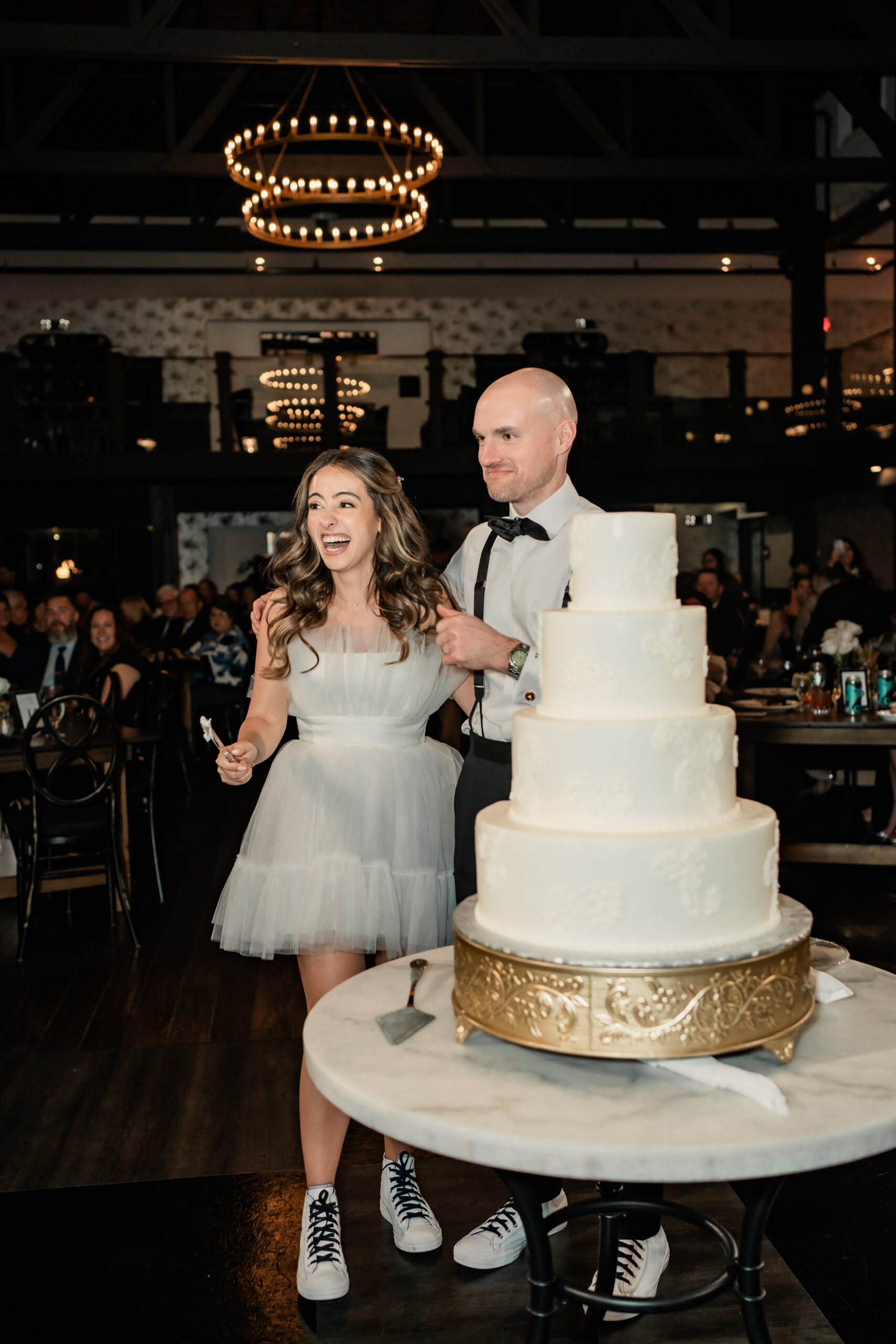 Park Loft wedding reception photography in Oceanport, NJ, showing the newlyweds cutting their tiered wedding cake after the bride changed into a short reception dress.